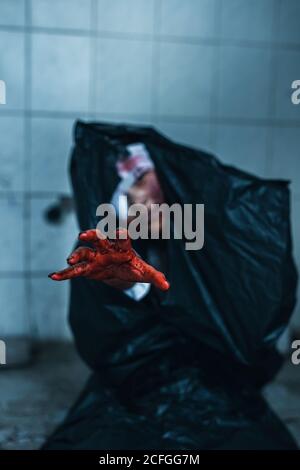 terrore scence di donna in un sacchetto nero di spazzatura con la mano spaventosa a casa abbandonata. Concetto di Halloween Foto Stock