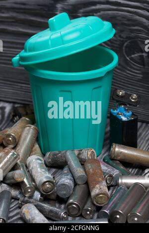 Batterie usate corrose. Nelle vicinanze c'è un cestino. Su tavole di pino. Smaltimento di rifiuti pericolosi. Foto Stock