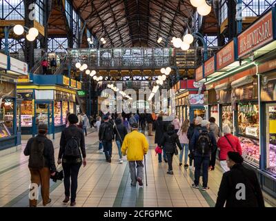 Una folla di molte persone, turisti e gente del posto attraverso e negozi presso le bancarelle del mercato del Grande mercato a Budapest. Foto Stock