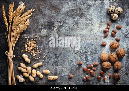 Regali di vendemmia autunnale. Spighe mature dorate di piante di grano, grani, arachidi, noci, nocciole e uova di quaglie su fondo di metallo rustico. Vista dall'alto e. Foto Stock