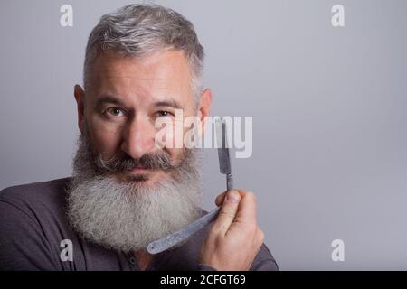 Ritratto di uomo maturo con rasoio retrò, concetto di barbiere, fuoco selettivo Foto Stock