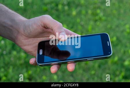 mano dell'uomo che tiene il riflesso del telefono cellulare sullo schermo Foto Stock