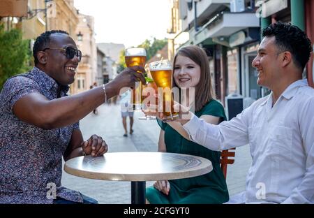 Gruppo multirazziale di amici che beve e tostano sulla terrazza della strada del caffè. Concetto di amicizia con giovani multietnici che godono di tempo toge Foto Stock