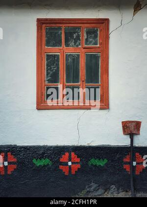 Finestra di legno di colore marrone incorniciata in una parete fessurata dipinta con calce blu chiaro. Primo piano dettagli architettonici di una vecchia casa tradizionale in mol Foto Stock