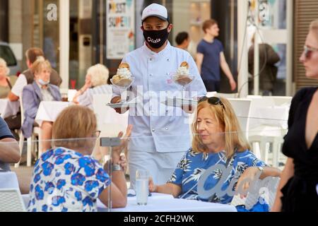 (200905) -- VIENNA, 5 settembre 2020 (Xinhua) -- UN cameriere che indossa una maschera per il viso serve un tavolo in un ristorante a Vienna, Austria, il 5 settembre 2020. Il sistema COVID-19 "semaforo" è ufficialmente operativo in Austria, il governo ha annunciato venerdì. A causa del numero costantemente elevato di nuove infezioni, le tre grandi città austriache -- Vienna, Linz e Graz -- Come pure il distretto tirolese di Kufstein si illuminano in giallo (medio rischio), mentre il resto del paese è designato 'verde' (basso rischio), secondo una conferenza stampa tenuta dal cancelliere Sebastian Kurz e da altri governanti Foto Stock