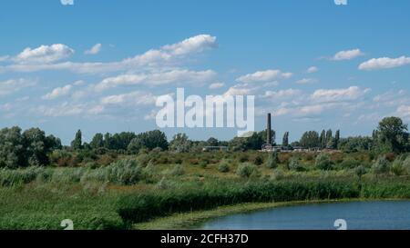 Lago di fronte a un piccolo villaggio in un paesaggio olandese polder, l'Ooijpolder in Gelderland, Olanda Foto Stock