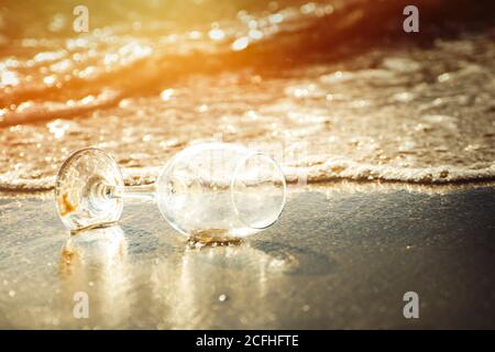 bicchiere di vino in spiaggia e acqua di mare in ingresso ora d'oro Foto Stock