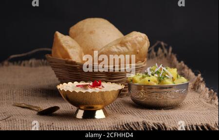 Puri/Bhaji e kheer - ricetta indiana semi secca di patata speziata conosciuta anche come Batata o Aloo ki Sabji, servita con Poori e khir fritti Foto Stock