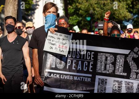 Washington, DC, USA, 5 settembre 2020. Nella foto: Un uomo che porta la bandiera della materia Black Lives porta anche un segno che dice,' l'arco dell'universo morale non si è mai piegato verso la giustizia da solo,' durante la marcia per la giustizia in memoria di Deon Kay. Deon Kay era un adolescente ucciso dalla polizia metropolitana (DC) all'inizio della settimana. L'uccisione è controversa perché la polizia ha rilasciato resoconti contraddittori dell'uccisione. Credito: Allison C Bailey/Alamy Foto Stock