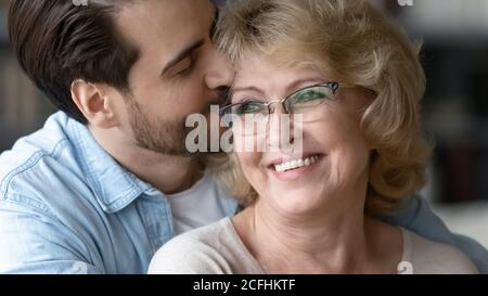 Primo piano figlio adulto baciando bella madre matura indossare occhiali Foto Stock