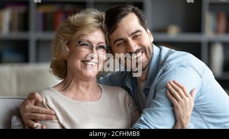 Adulta la donna matura e il figlio adulto che si abbracciano, in posa per una foto Foto Stock