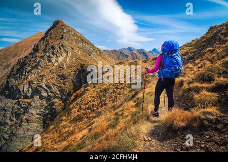 Donna allegra escursionista con zaino godendo la vista sul sentiero escursionistico, montagne Fagaras, trekking e concetto di viaggio, Carpazi, Romania, Europa Foto Stock
