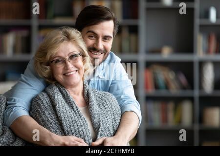 Testa ritratto girato sorridendo donna matura e giovane uomo abbracciando Foto Stock