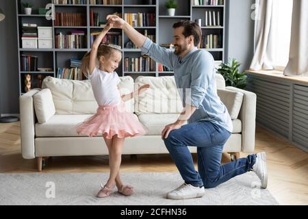 Padre amorevole in piedi sul ginocchio, tenendo adorabile mano piccola figlia Foto Stock