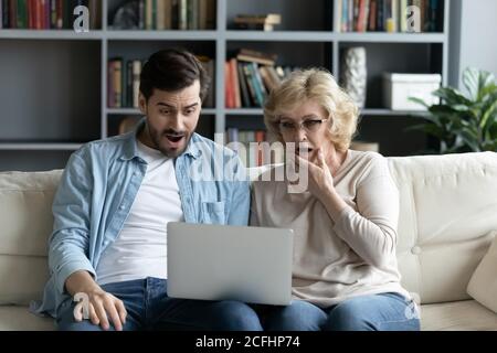 Donna matura e giovane uomo scioccato che guarda lo schermo del notebook Foto Stock