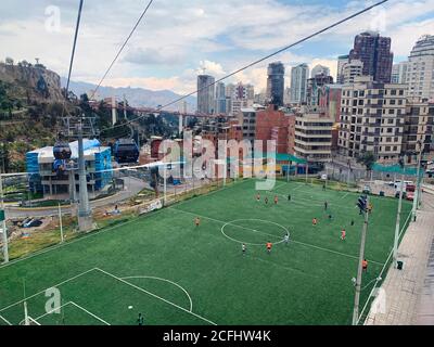 Vista aerea sulla città di Laz Paz, capitale della Bolivia. Trasporto in funivia. Paesaggio panoramico della città boliviana. Gioco di calcio allo stadio. Foto Stock