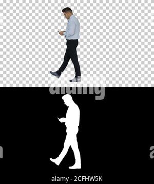 Uomo maturo che cammina e utilizza il telefono cellulare, canale Alpha Foto Stock