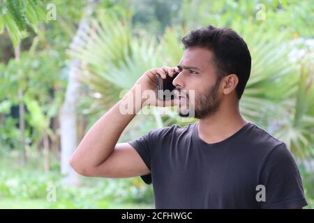 Ritratto di un giovane che parla sul telefono cellulare e. aspetto scioccato Foto Stock