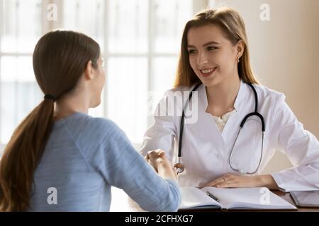 Sorridente dottore femmina che scuotono la mano della paziente al meeting Foto Stock