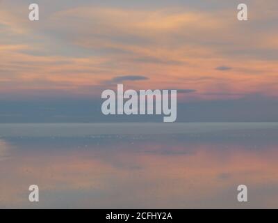 Nuvoloso. Dolce alba sul lago salato. Nuvole riflesse sulle distese saline di Uyuni in Bolivia. Cielo tenera di colore. Bellissimo paesaggio mattutino. Foto Stock