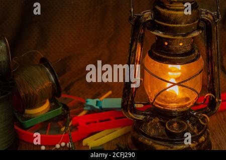 lenza da pesca, ganci, platine, attrezzi illuminati da un'antica lampada a cherosene Foto Stock
