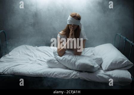 Donna pazza bendata a letto, psichedelica Foto Stock