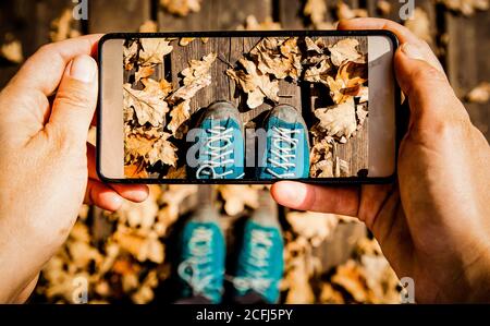 instagrammer scattare una foto delle sue scarpe da trekking e caduta fogliame Foto Stock