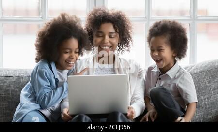 Felice giovane donna africana che guarda il film sul computer con i bambini. Foto Stock
