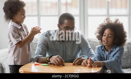 Felice giovane etnia africana padre giocare con plastilina con bambini. Foto Stock