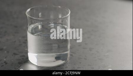 pulire l'acqua fresca nel bicchiere di vetro sul piano di cemento, foto larga Foto Stock