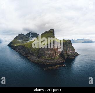 Veduta aerea del drone delle isole Kalsoy sulle isole Faroe. Panorama aereo di un piccolo faro bianco situato sul bordo di un'enorme scogliera e l'isola Foto Stock