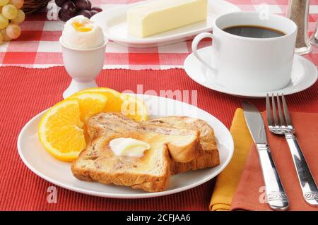 La colazione comprende toast alla cannella, fette d'arancia e un uovo bollito morbido Foto Stock