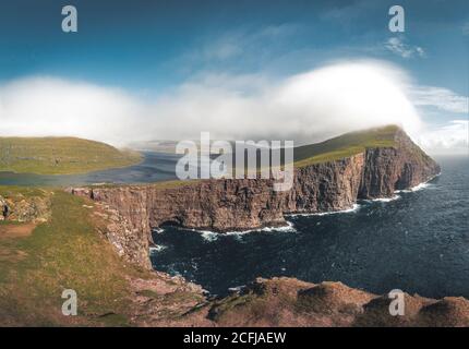 Faroe Islands Traelanipa la scogliera di roccia degli schiavi si vede innalzarsi sopra l'oceano vicino al lago Sorvagsvatn. Nuvole e cielo blu durante suommer sul Foto Stock