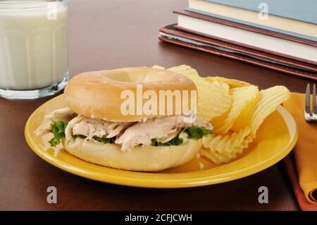 Un panino di pollo su un bagel come dopo la scuola snack con latte Foto Stock