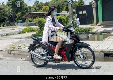 NAKHON NAYOK, THAILANDIA, LUGLIO 05 2020, UNA giovane donna che guida una moto su strada. Ragazza asiatica ride scooter nella strada della città. Foto Stock