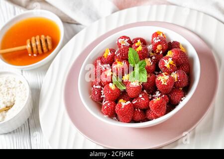 Razzi di lamponi da dessert vegetariani, senza latte, ripieni di cocco grattugiato e scorza d'arancia, serviti su piatti bianchi e rosa con Foto Stock