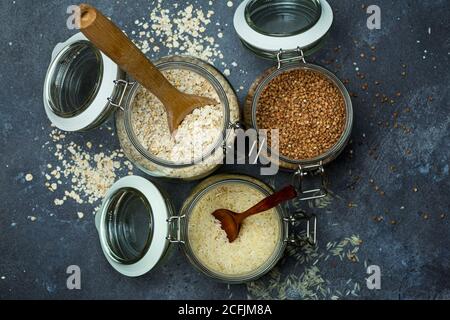 Cereali (farinata d'avena, grano saraceno, riso) in vasi di vetro in cucina. Concetto senza glutine. Varietà di cereali per la preparazione di cibi e pasti sani fatti in casa. Foto Stock