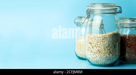 Cereali (farinata d'avena, grano saraceno, riso) in vasi di vetro in cucina. Concetto senza glutine. Varietà di cereali per la preparazione di cibi e pasti sani fatti in casa. Foto Stock