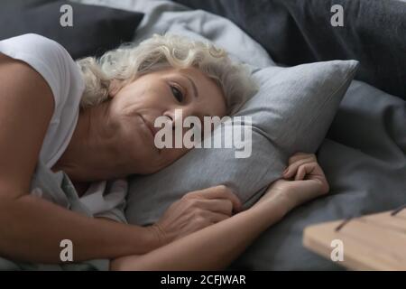 Primo piano bella donna matura sdraiata a letto dopo il risveglio Foto Stock