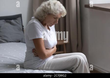 Donna matura frustrata che tiene il ventre, che soffre di bellyache Foto Stock