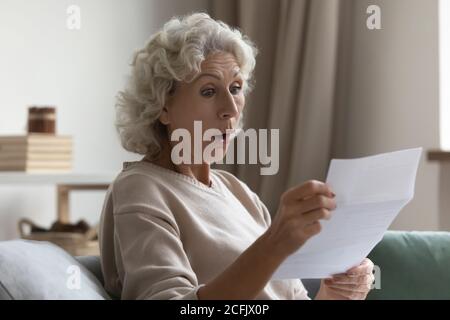 Stupito scioccato donna matura con bocca aperta lettura lettera Foto Stock