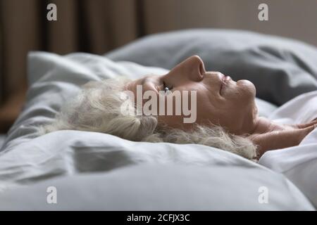 Primo piano sconvolto donna di mezza età sdraiata a letto Foto Stock