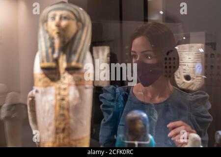 Un visitatore che indossa una maschera per il viso a causa del coronavirus COVID-19 Pandemic viste antiche statue egiziane esposte presso l'Ala Archeologia Del Museo di Israele a Gerusalemme Ovest Israele Foto Stock