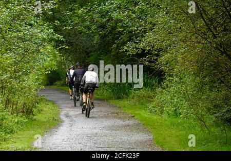 Tre ciclisti sul Sett Valley Trail, che corre tra New Mills e Hayfield nel Derbyshire Foto Stock