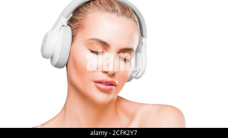 Ritratto di una bella donna in cuffia bianca che ascolta la musica con gli occhi chiusi su sfondo bianco Foto Stock
