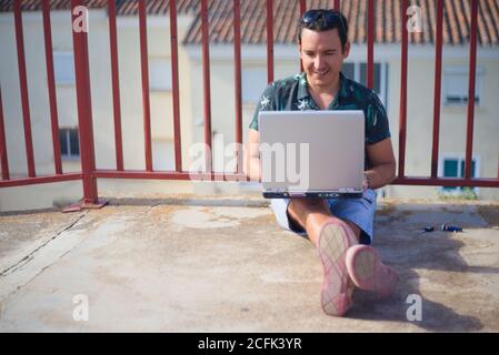 Uomo che telelavoro online all'aperto con un computer portatile. Foto Stock