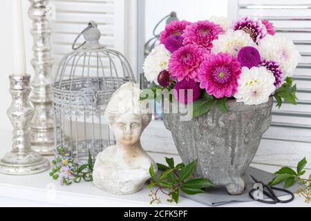 decorazione vintage con bouquet di fiori di dahlia in rosa e bianco, busto donna e gabbia di uccelli Foto Stock