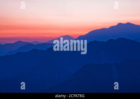 Strati di magnifiche montagne all'alba con nuvole colorate sullo sfondo Foto Stock