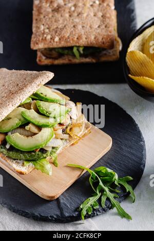 Gustoso sandwich con avocado posto sul tavolo con un bicchiere di birra e patatine al caffè Foto Stock