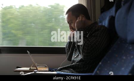 Medio shot.Man smalti le piccole cuffie bianche durante un viaggio in treno. Riprese professionali con risoluzione 4K. 02. Può essere utilizzato, ad esempio, nel vostro vi commerciale Foto Stock